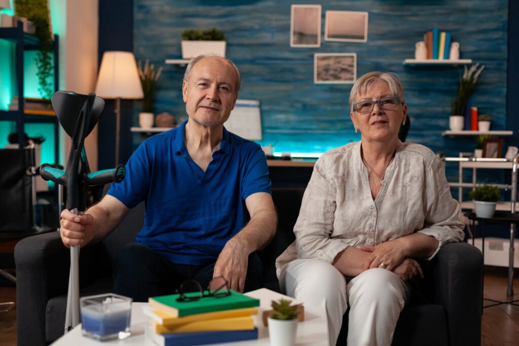 Ein Mann mit Unterarmgehstütze und eine Frau sitzen gemeinsam auf einem Sofa in Bochum